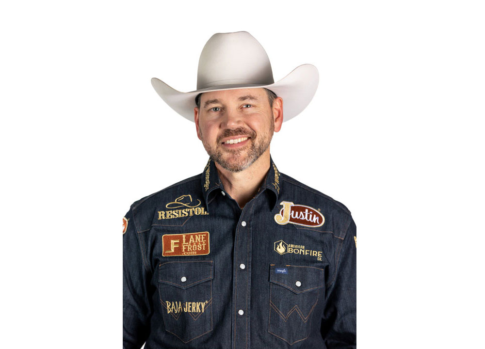 El barrendero profesional Matt Merritt, vestido con una camisa vaquera, un sombrero de vaquero blanco y sonriendo, frente a una pared blanca.